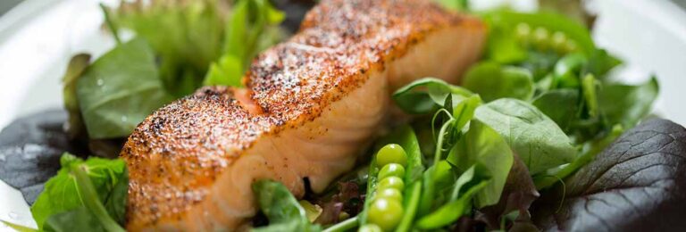 Seared salmon fillet on a bed of leafy greens