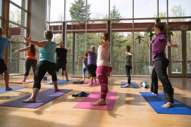 Women stretching on yoga mats during a class in a sunlit studio