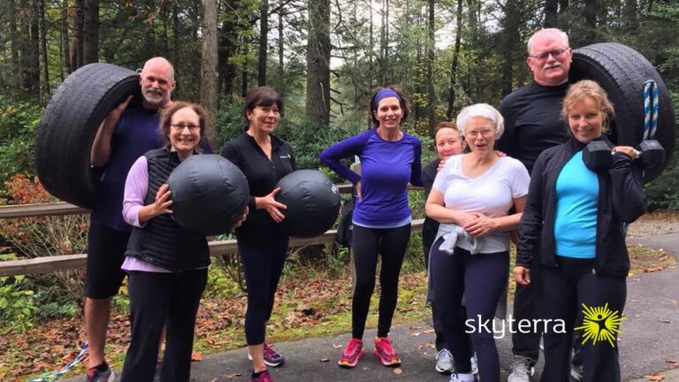 Smiling group of guests holding medicine balls on a wooded road