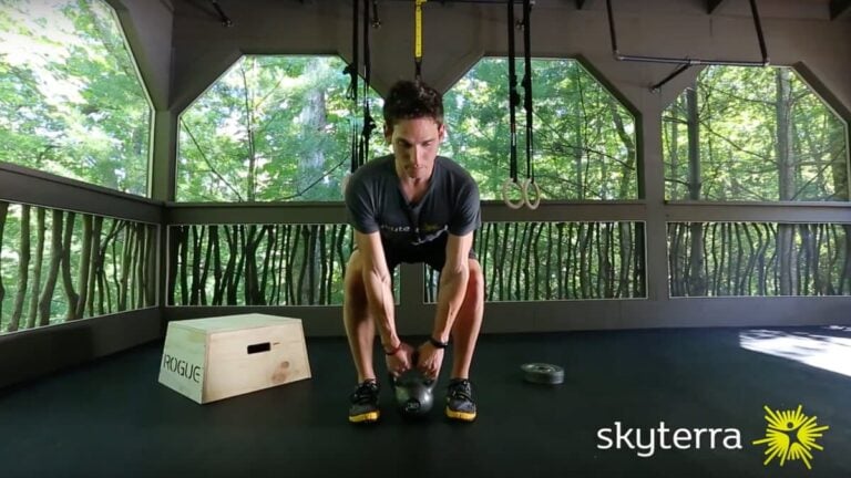 Man lifting a kettlebell in an open-air workout pavilion