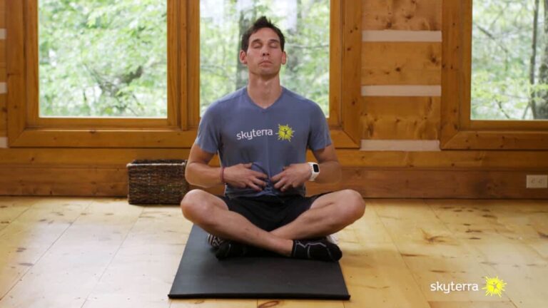 Man meditating cross-legged on a mat in a wood-paneled studio