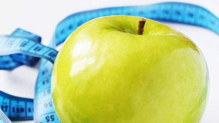 Green apple wrapped with a blue measuring tape