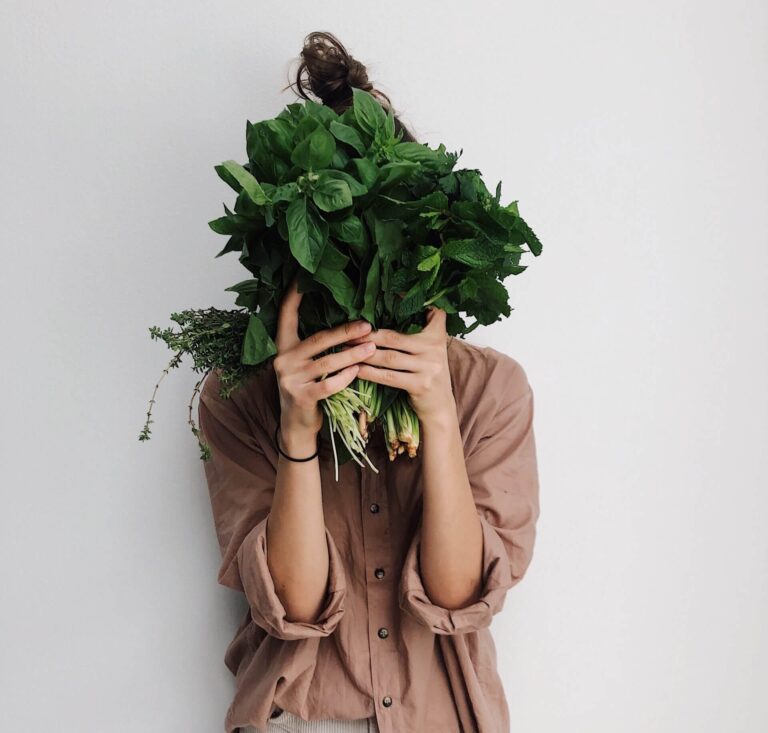 Woman holding a bunch of leafy greens in front of her face
