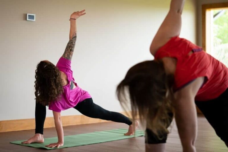 Women in a twisting lunge yoga pose in a sunlit studio