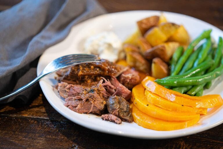 Plate of sliced steak, roasted potatoes, green beans and squash