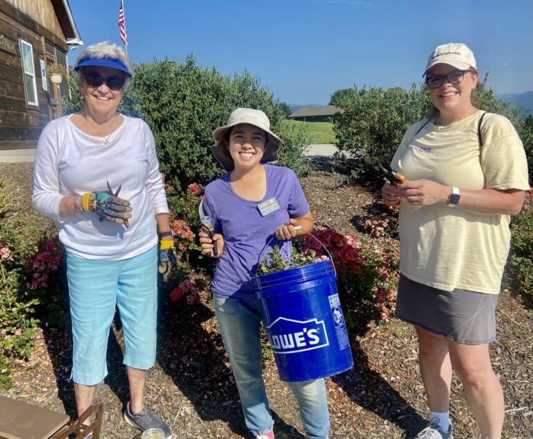 Three guests holding gardening tools and a bucket in the Skyterra garden