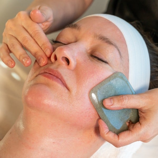 Guest receiving a facial with a jade stone from a Skyterra esthetician
