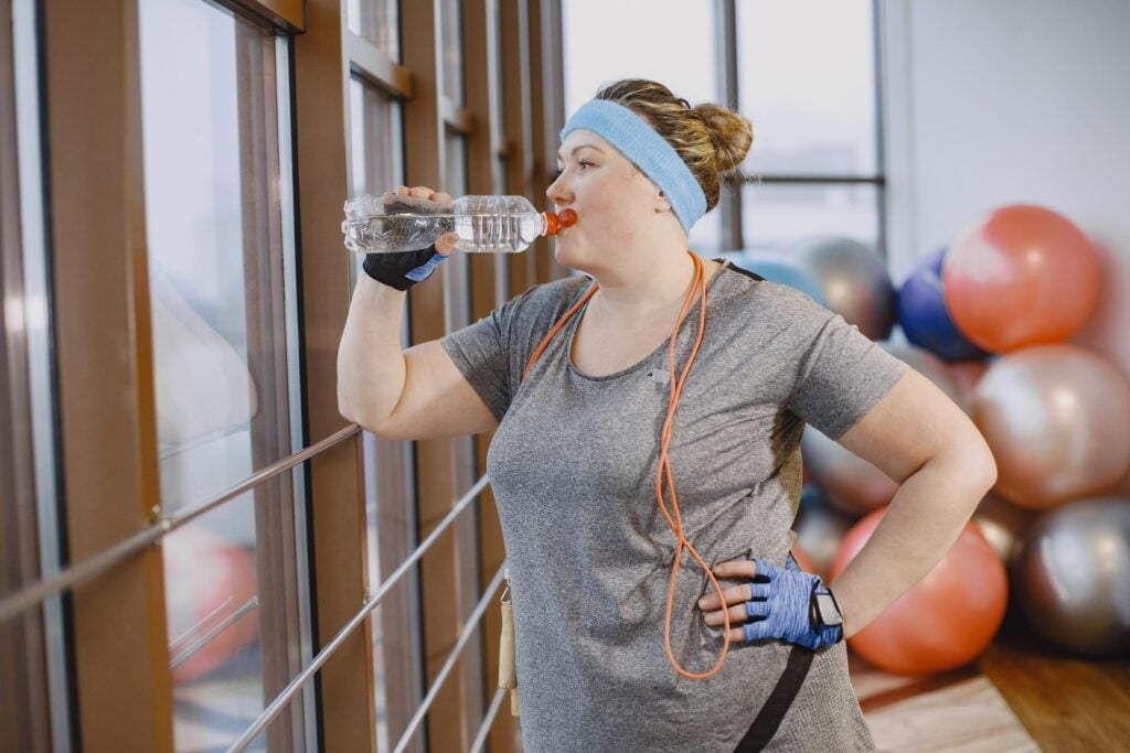 Woman drinking from a water bottle after a workout in the fitness studio