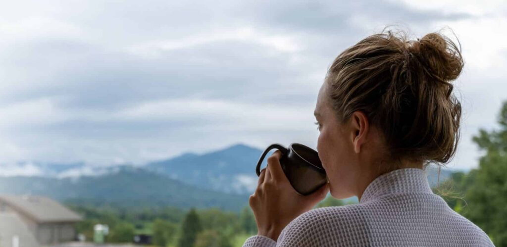 Woman sipping coffee with a misty mountain view