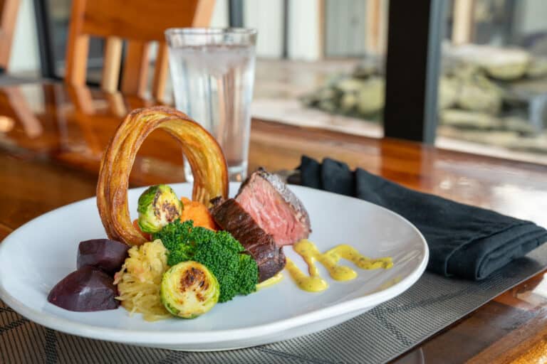 Sliced steak with roasted vegetables and a crispy onion ring