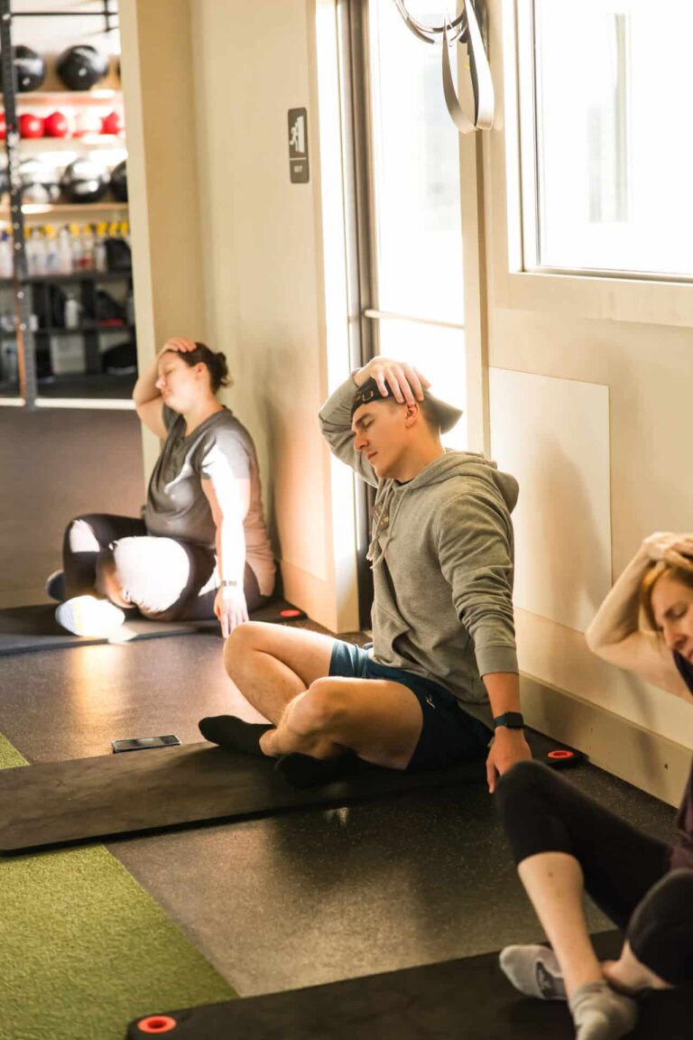 Guests resting and stretching on mats after a fitness class