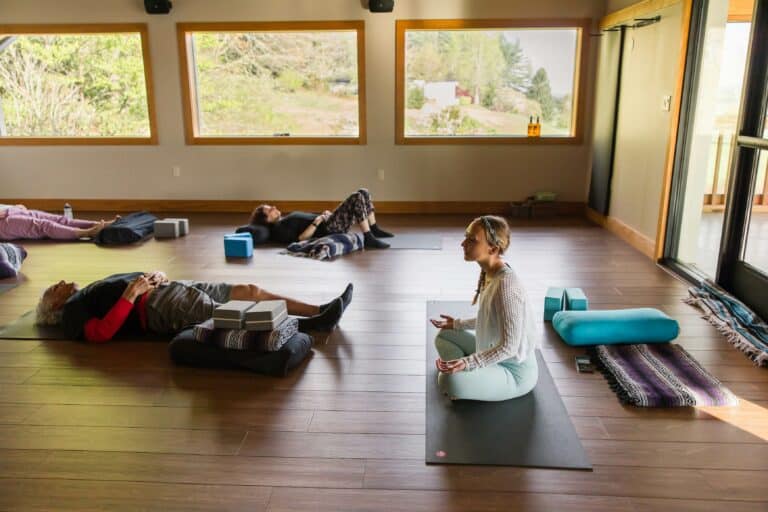 Guests resting on mats during a restorative class in a sunlit studio