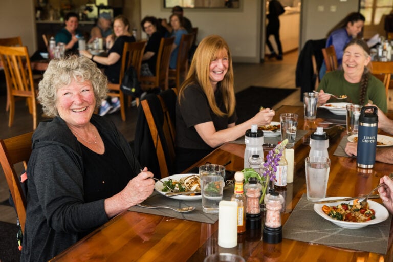 Guests smiling over a shared meal at a long dining table