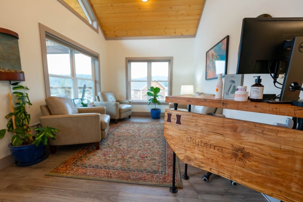 Spa reception with a wood desk, armchairs and tall windows