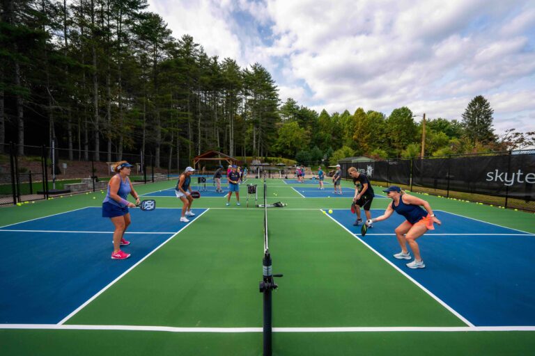 Guests playing doubles on Skyterra's outdoor pickleball courts surrounded by pine trees