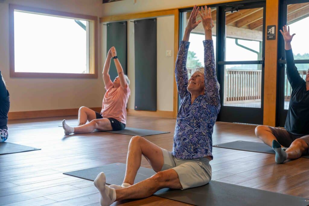 Guests stretching on yoga mats in a sunlit studio