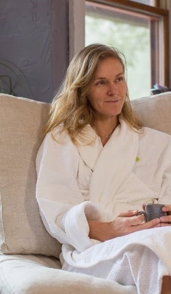 Guest in a white robe relaxing with a warm drink in the spa