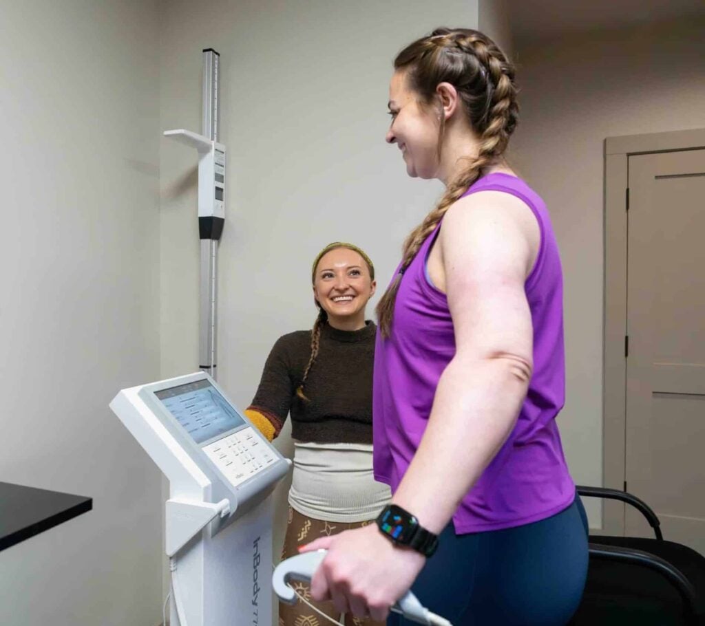 Guest stepping onto an InBody scanner while a Skyterra team member looks on